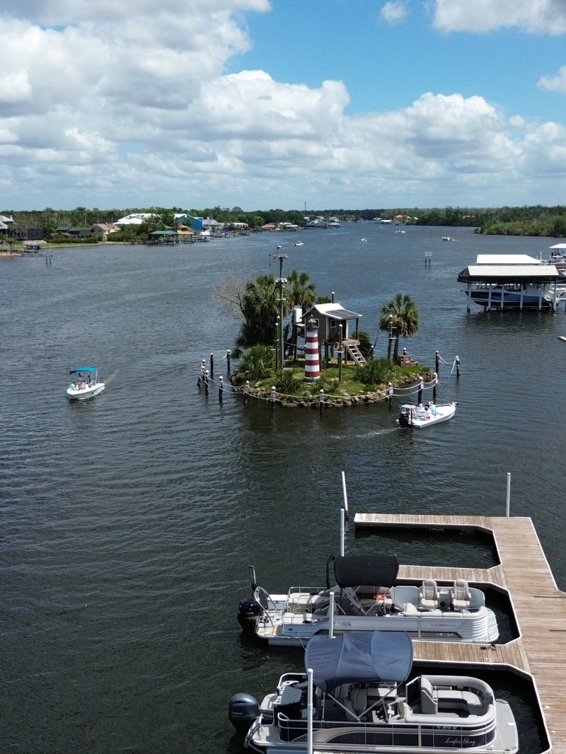 Aerial view of a river with docks, boats, and houses on a cloudy day.