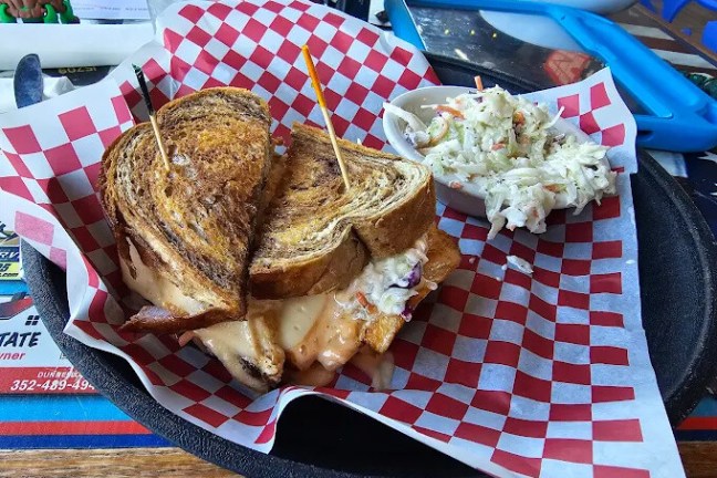 Grilled sandwich with coleslaw on red checkered paper.